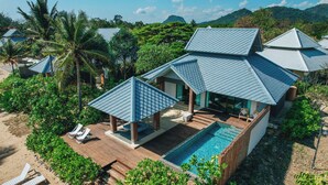 A resort with multiple bungalow-style buildings, a swimming pool, and a beach area with lounge chairs. - Sirarun Resort (Thap Sakae)