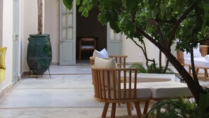 Un patio con una mesa y sillas de madera, una planta en maceta y un arco de entrada.