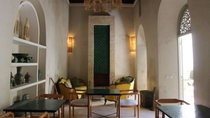 Una habitación con chimenea, zona de estar y estantes con adornos.