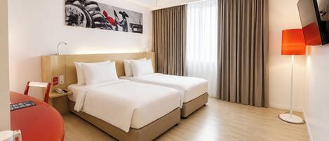Habitación de hotel con dos camas, un escritorio con silla, televisor de pantalla plana y un cuadro en la pared.