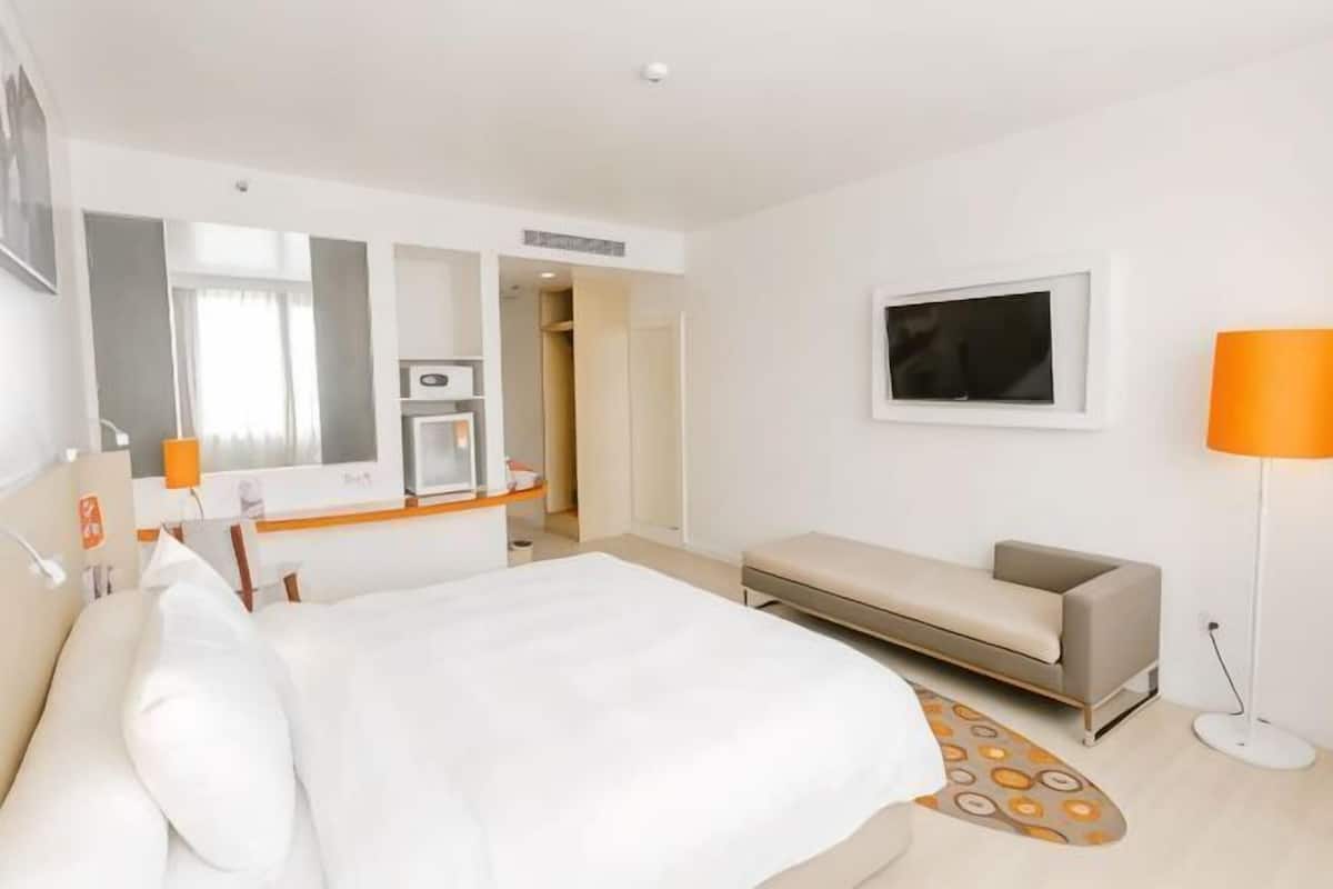 Une chambre d’hôtel comprenant un lit, un canapé, un bureau avec un miroir, une lampe et un téléviseur.
