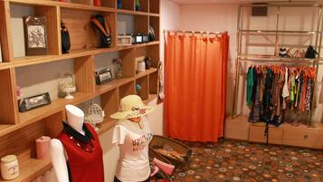 Quarto com estantes de madeira, um manequim, um cabideiro e chão estampado.