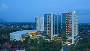 A modern hotel complex with multiple high-rise buildings, featuring a distinctive curved building on the left. - The Alana Yogyakarta Hotel and Convention Center (Ngaglik)