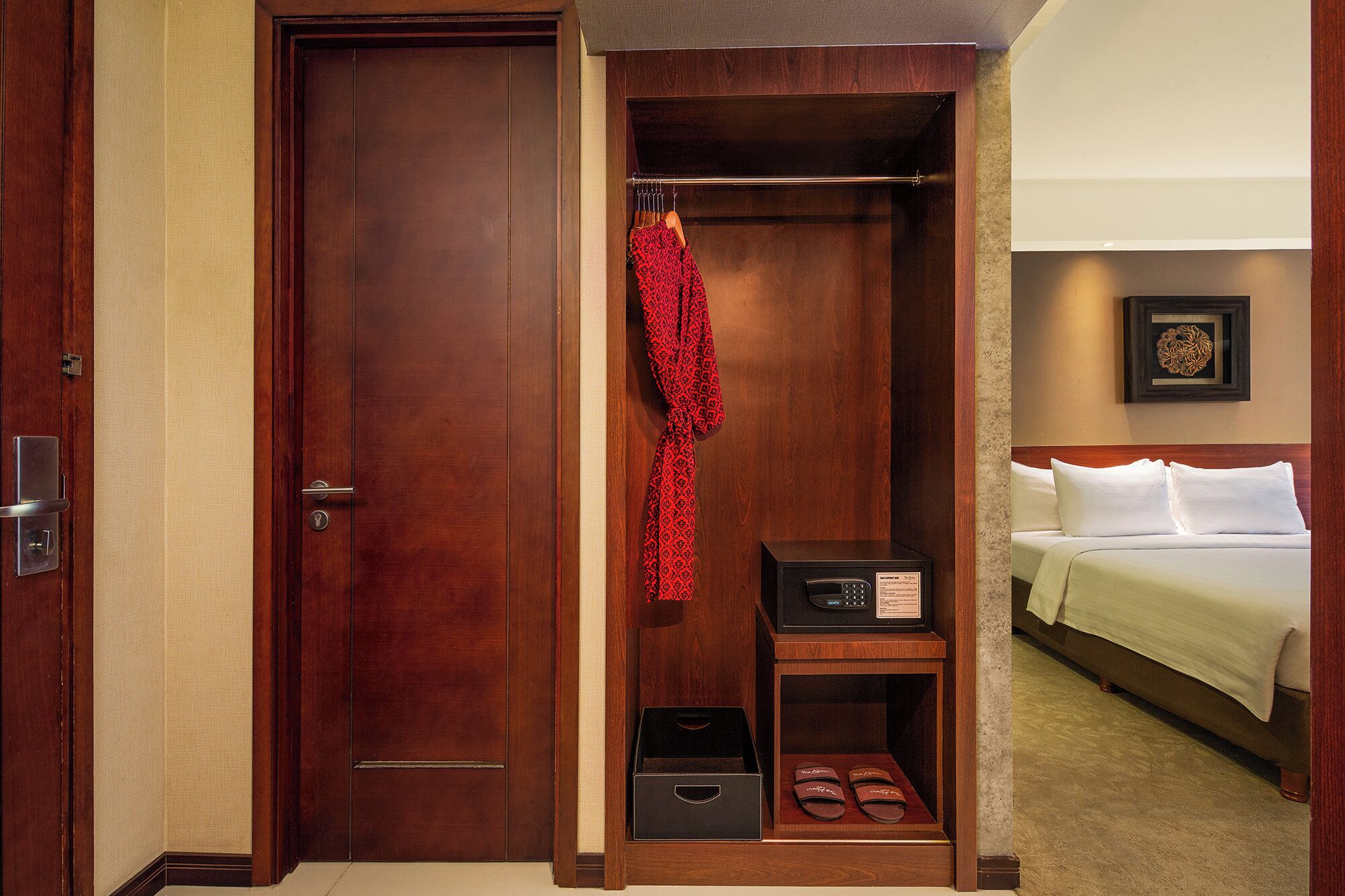 Habitación de hotel con un armario de madera, una cama con ropa blanca y un cuadro en la pared.