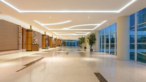 Um hall amplo com design moderno, apresentando um corredor longo, lambris de madeira e janelas grandes.