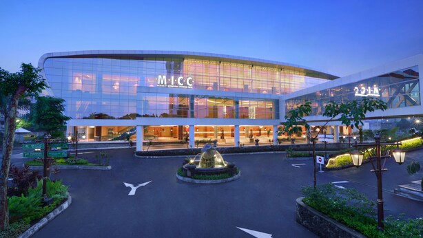 Um edifício moderno com fachada de vidro e o texto "MCC" em destaque.