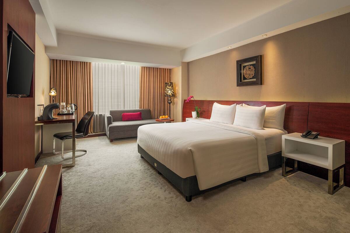 A hotel room with a bed, desk, chair, and a television.