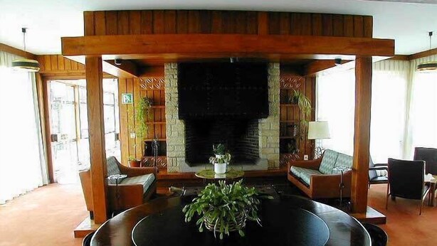 A dining area with a black table, surrounded by chairs, and a fireplace in the background. - Hotel San Ángel (Ribadedeva)