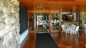 A wooden interior with a stone wall, a tiled floor, and a seating area with chairs. - Hotel San Ángel (Ribadedeva)