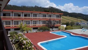 A hotel with a swimming pool, a red-roofed building, and a mountainous backdrop. - Hotel San Ángel (Ribadedeva)