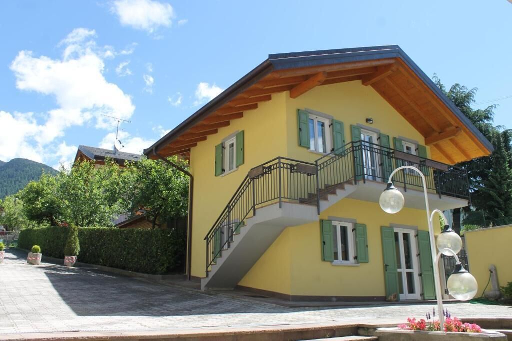 A yellow building with a balcony, a staircase, and a street lamp.