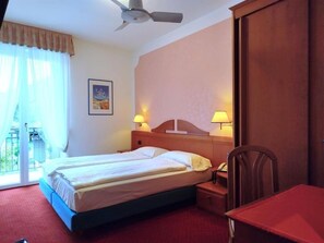 Une chambre d’hôtel équipée d’un lit, de lampes de chevet, d’un bureau, d’une chaise et d’un ventilateur de plafond.