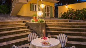 A dining area with a round table and four chairs, a candle, and a glass of wine. - Hotel Lucia (Levico Terme)