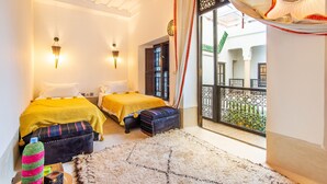 A hotel room with two beds, a balcony with a view, and a traditional decor style. - Dar Charkia (Marrakech)