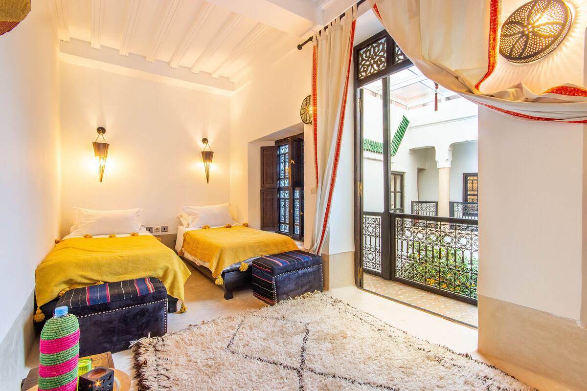 A hotel room with two beds, a balcony with a view, and a traditional decor style.