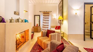 A cozy living room with a fireplace, a sofa, and a patterned rug. - Dar Charkia (Marrakech)