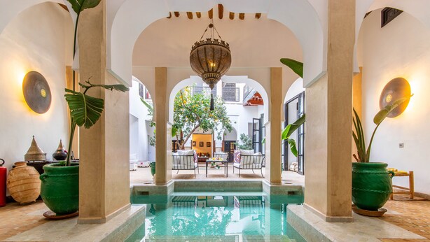 A pool area with a statue, columns, and a view of the interior. - Dar Charkia (Marrakech)