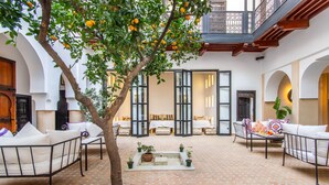 A courtyard with a tree, outdoor seating, and a view of the interior. - Dar Charkia (Marrakech)