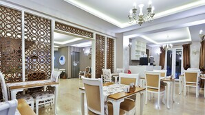 A dining area with white and brown chairs, a wooden table, and a decorative partition. - Enda Boutique Hotel (Kas)