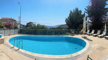 Alberca al aire libre, sombrillas en la alberca y camastros