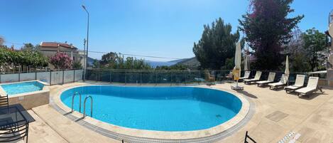 Een buitenzwembad, parasols voor strand/zwembad