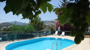 A swimming pool with a glass balustrade, surrounded by lounge chairs and a view of a hillside. - Enda Boutique Hotel (Kas)