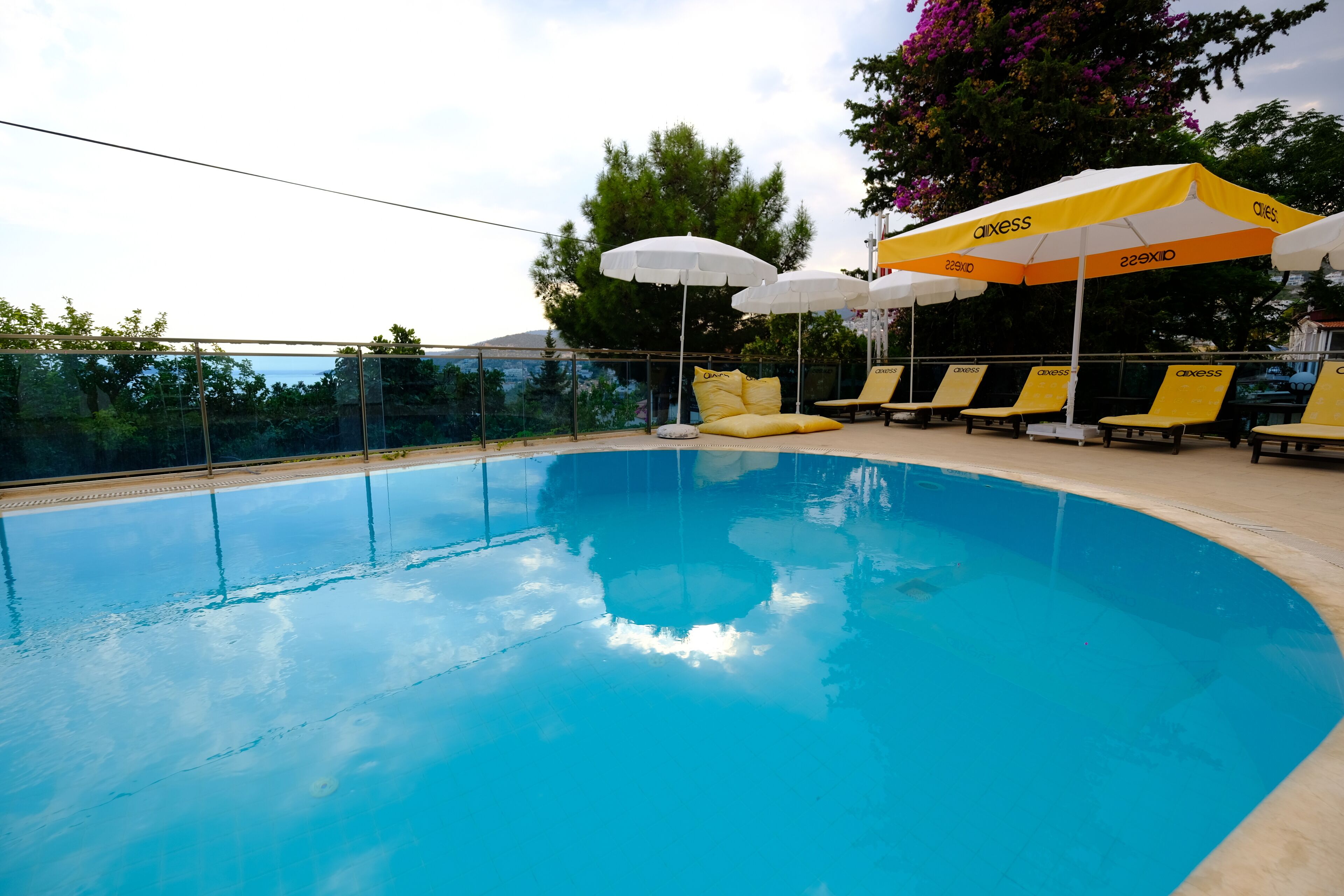 Una piscina al aire libre, sombrillas, sillones reclinables de piscina