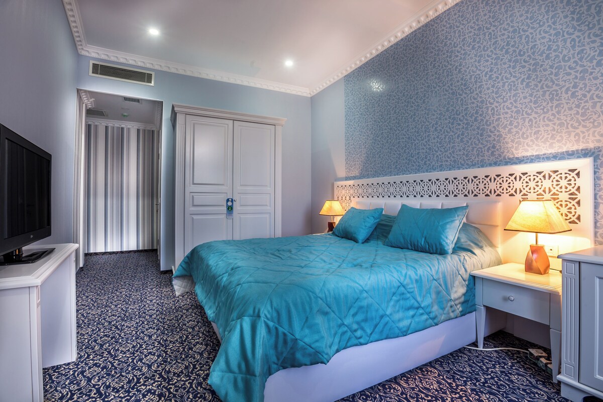Une chambre à coucher comprenant un lit, une télévision, une table de chevet et une porte donnant sur une autre pièce.