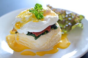 Un plato de desayuno con huevos pochados, espinacas y salsa sobre un plato blanco.