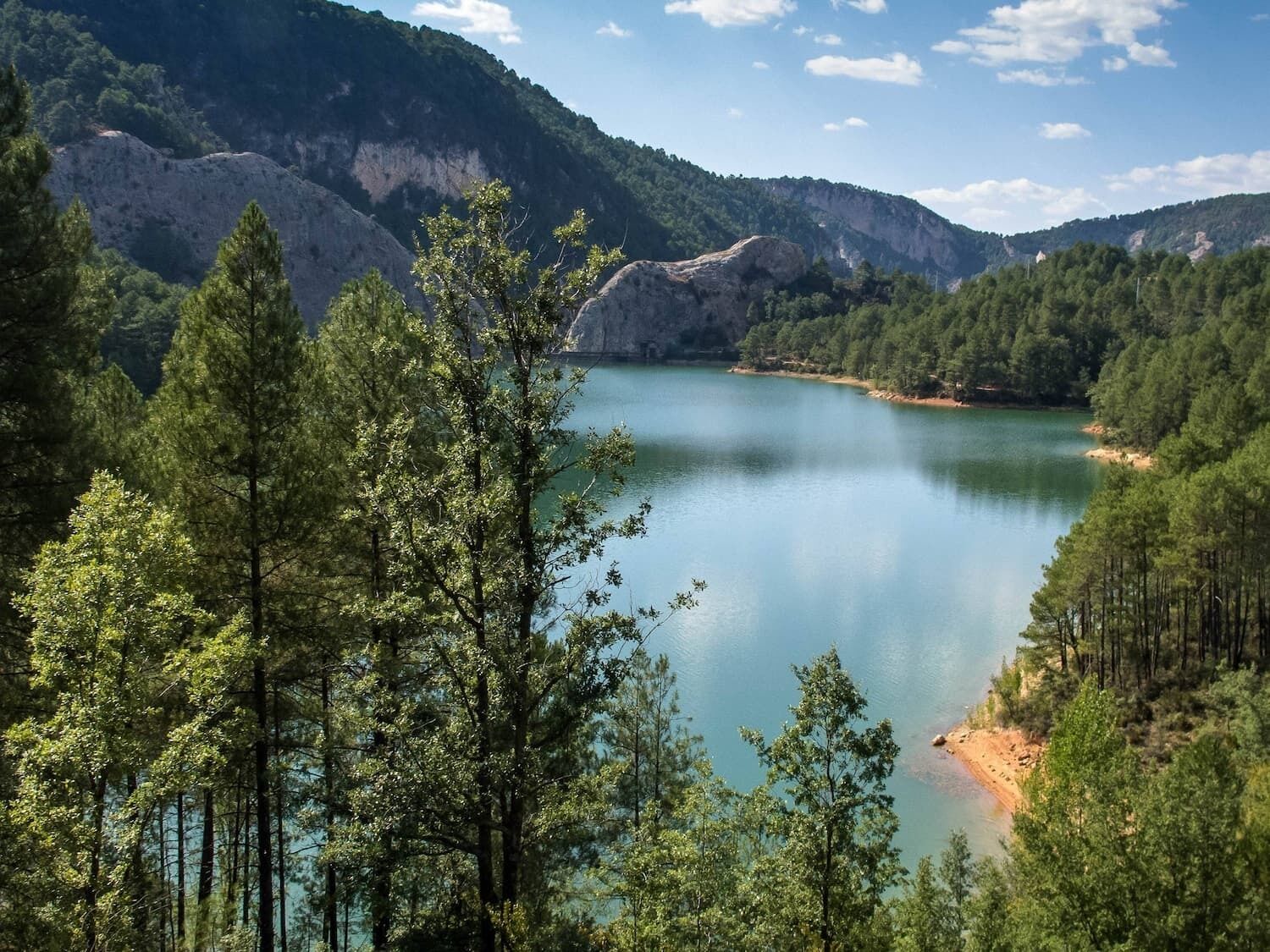 A serene lake surrounded by dense forest and rocky hills.