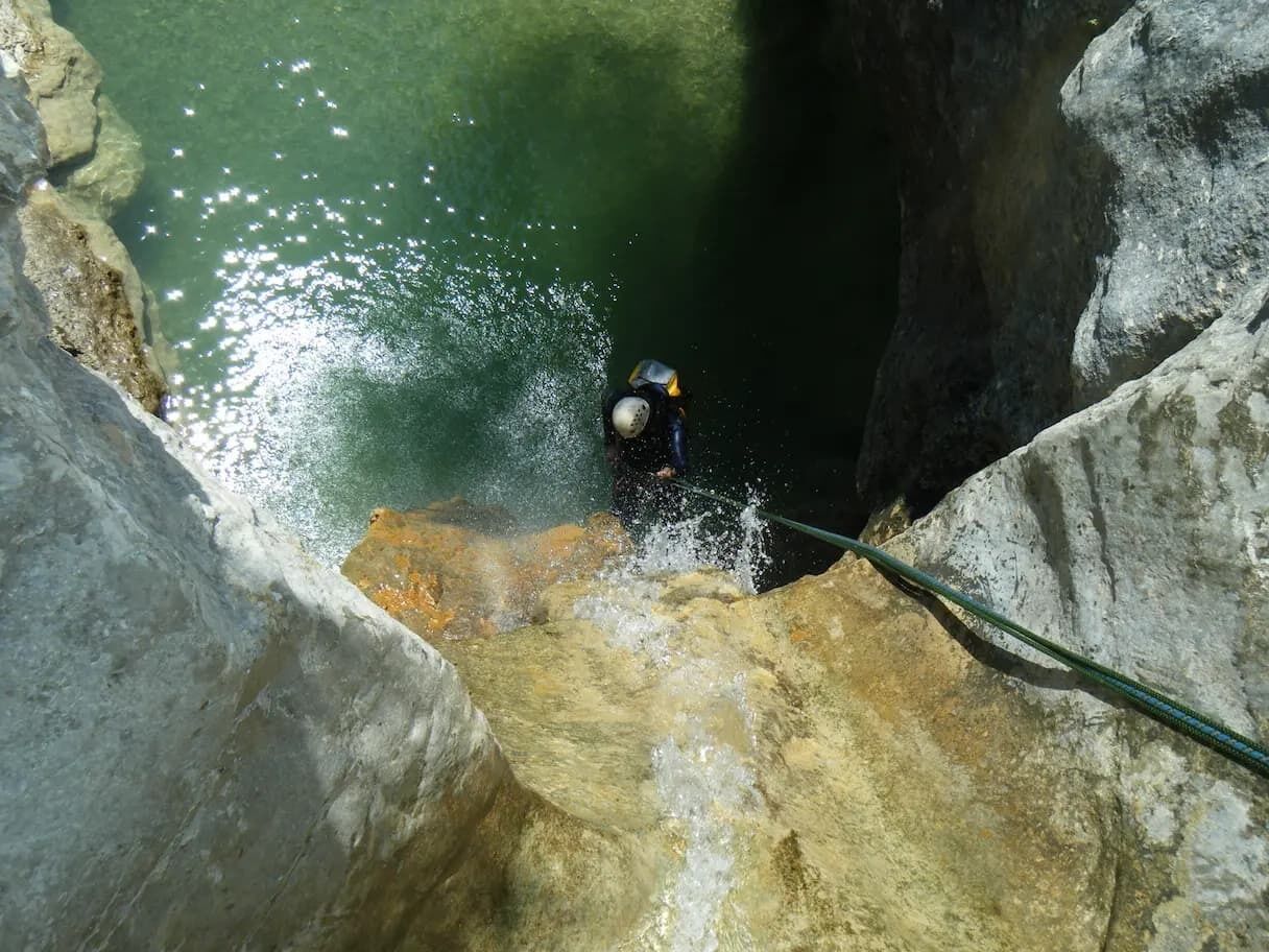 Un buceador en una cueva con una cuerda, rodeado de formaciones rocosas y agua.