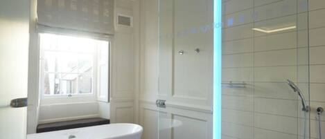 Un baño moderno con una bañera independiente, ducha con cerramiento de vidrio y ventana que proporciona luz natural.