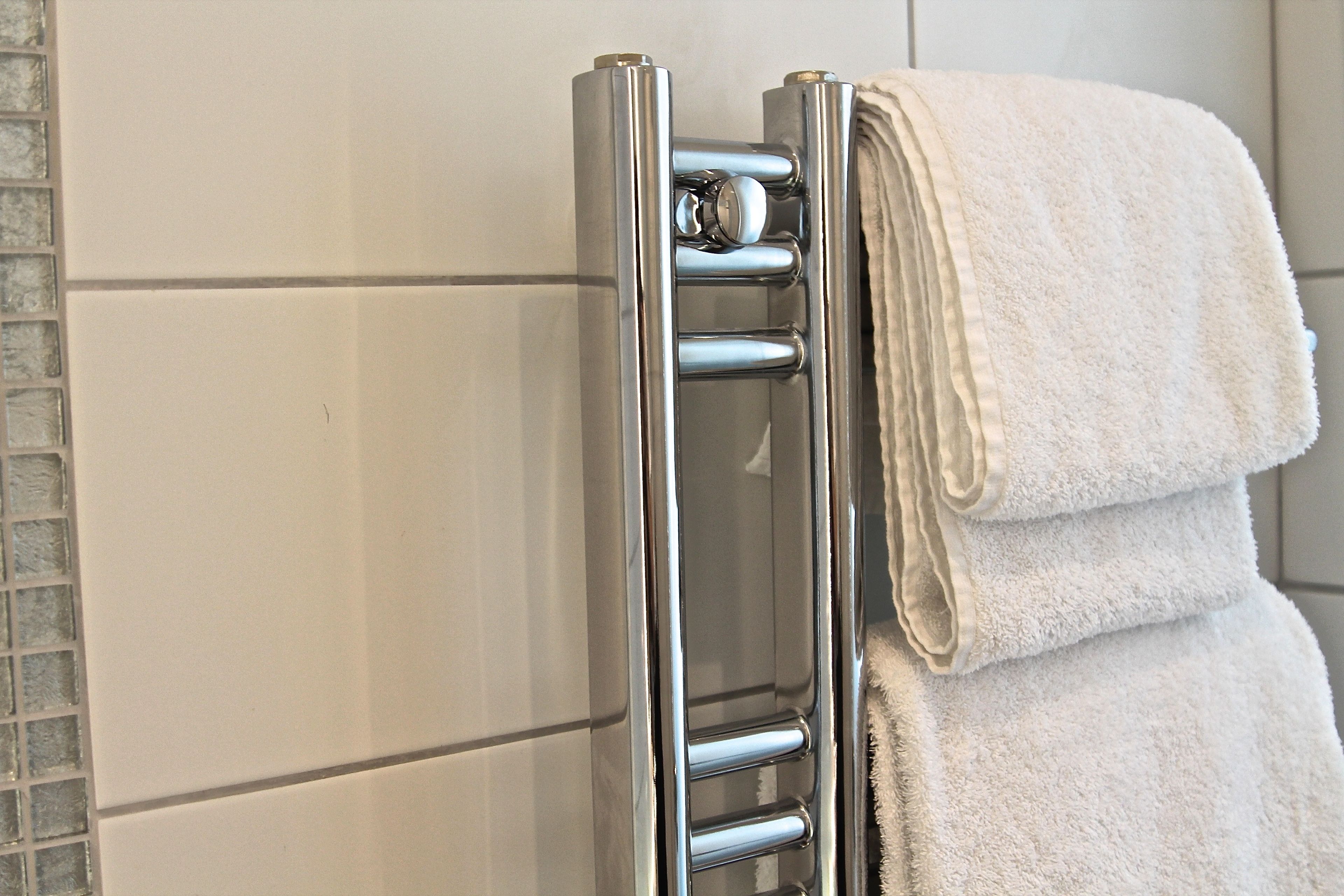 A chrome towel rail with two folded towels.