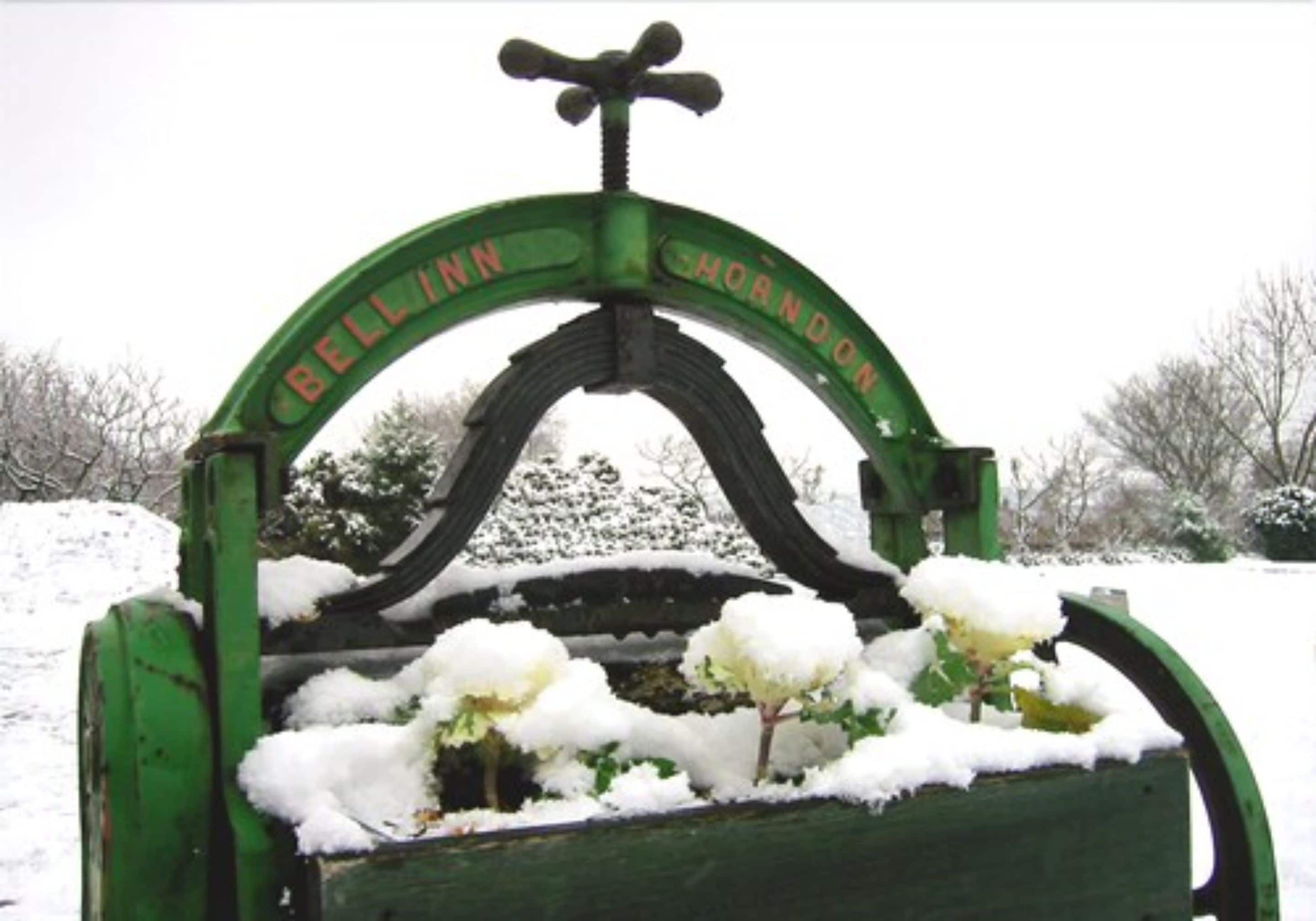 Une arche métallique verte portant l’inscription « BELLINN MORINDON » et surmontée d’une cloche.