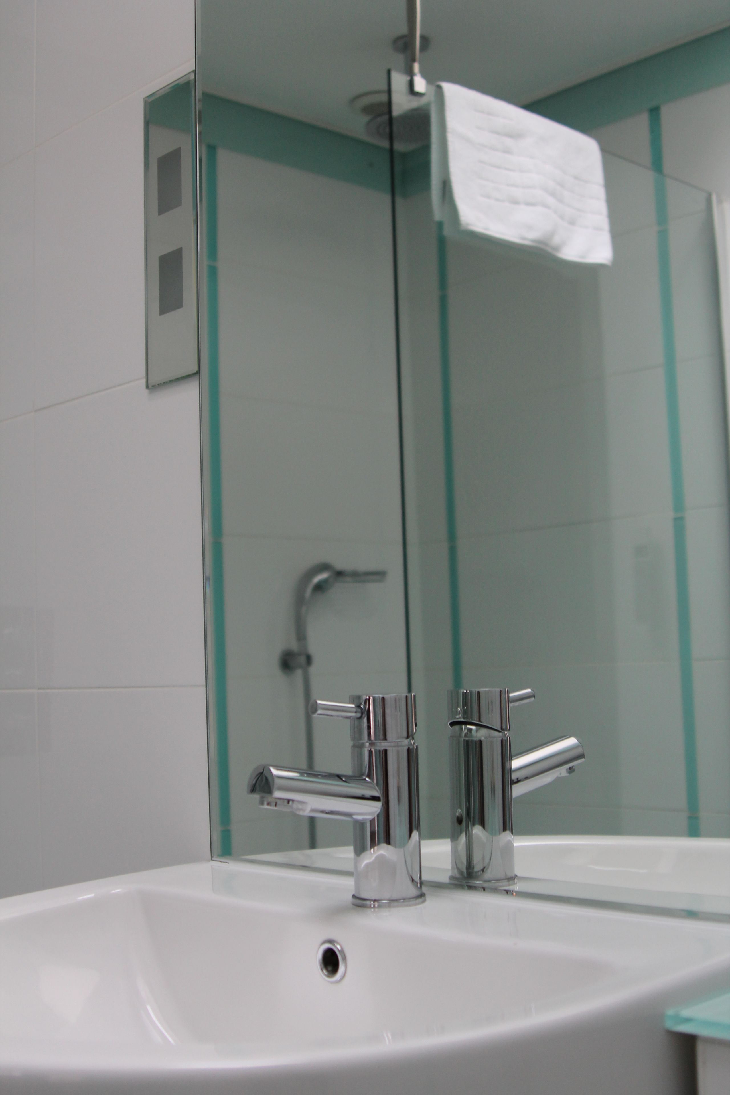 A bathroom with a white sink, chrome faucets, and a glass shower enclosure.