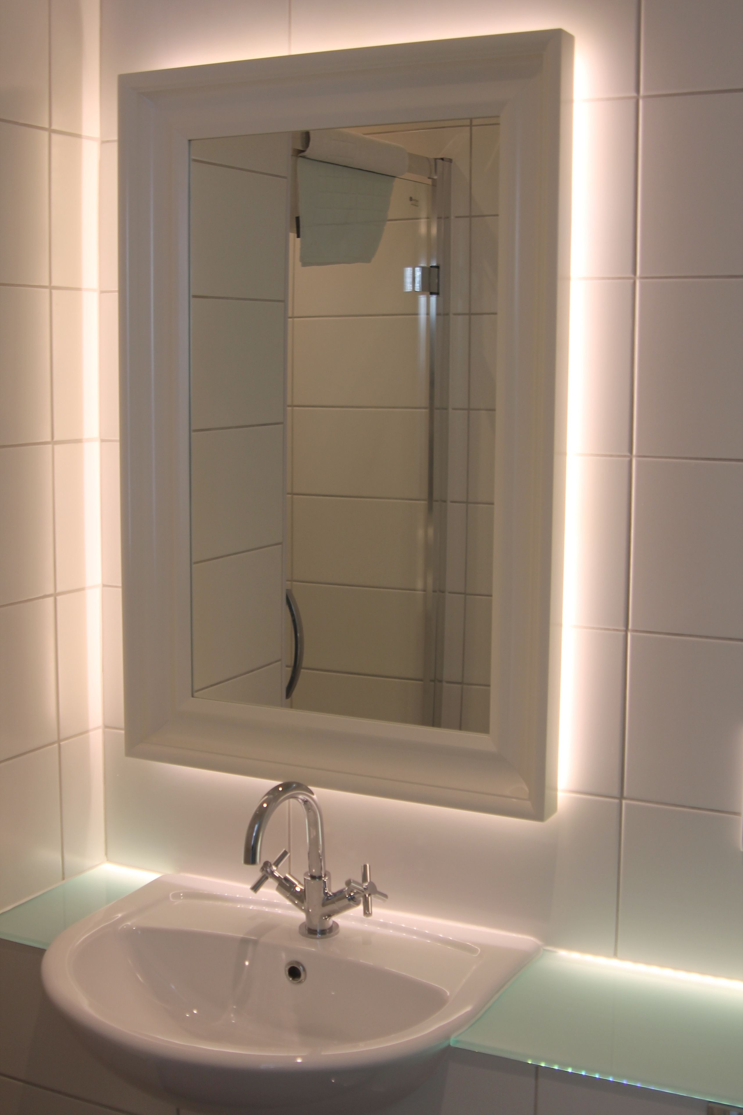Un baño con un lavabo blanco, un espejo y una encimera de vidrio.
