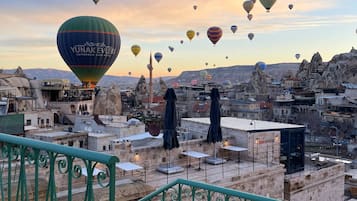 A rooftop terrace with a view of a cityscape and hot air balloons in the sky.