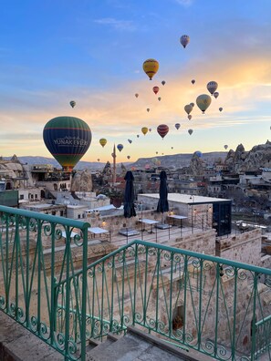 A rooftop terrace with a view of a cityscape and hot air balloons in the sky. - Gedik Cave Hotel (Nevsehir)