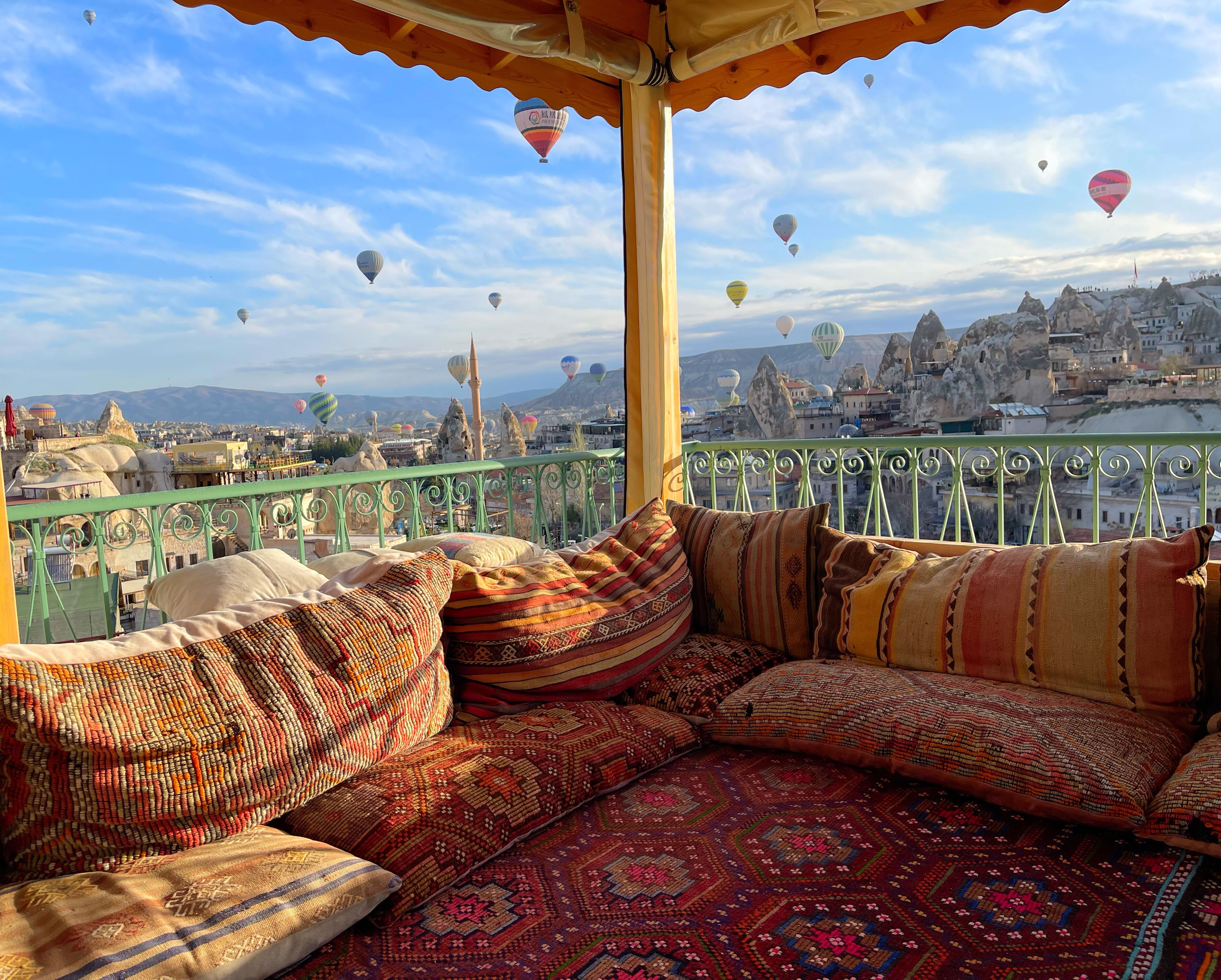 A balcony with a view of a cityscape and hot air balloons.