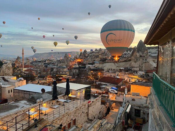 A cityscape with a view of a hot air balloon ride over a historic town with unique rock formations and traditional architecture. - Gedik Cave Hotel (Nevsehir)