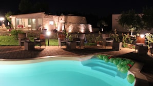 A swimming pool with green balloons, outdoor furniture, and a stone building in the background. - B&B La Vigna (Carovigno)