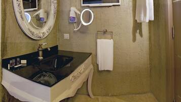 A bathroom with a vanity, sink, mirror, hairdryer, and towel rack.