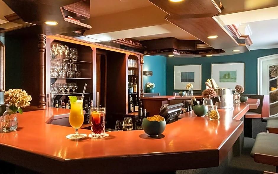 Un'area bar con un bancone in legno lucido, bicchieri e bottiglie.