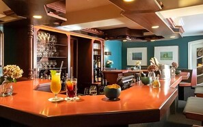 Eine Bar mit einer polierten Holztheke, Gläsern und Flaschen.