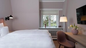 Ein Hotelzimmer mit Bett, Schreibtisch, Stuhl, Fenster mit Aussicht und Lampe.