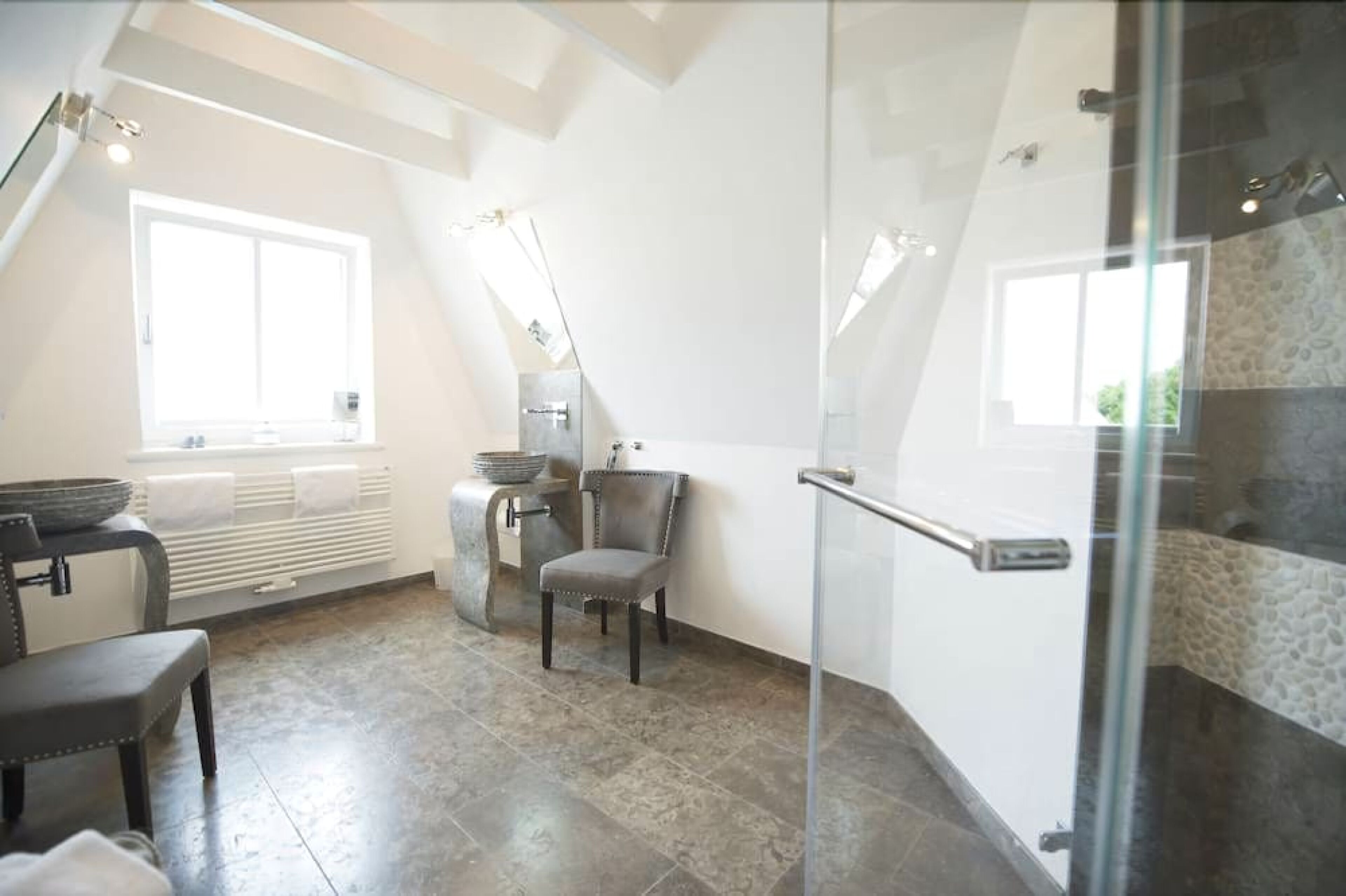 Une salle de bain moderne dotée d’une douche à parois de verre, d’un banc intégré et d’une grande fenêtre laissant entrer la lumière naturelle.