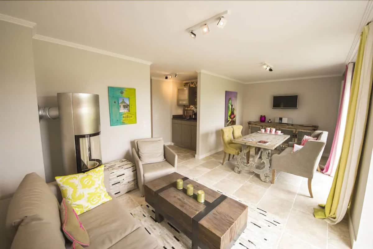 A living room with a sofa, coffee table, and a dining area with a table and chairs.