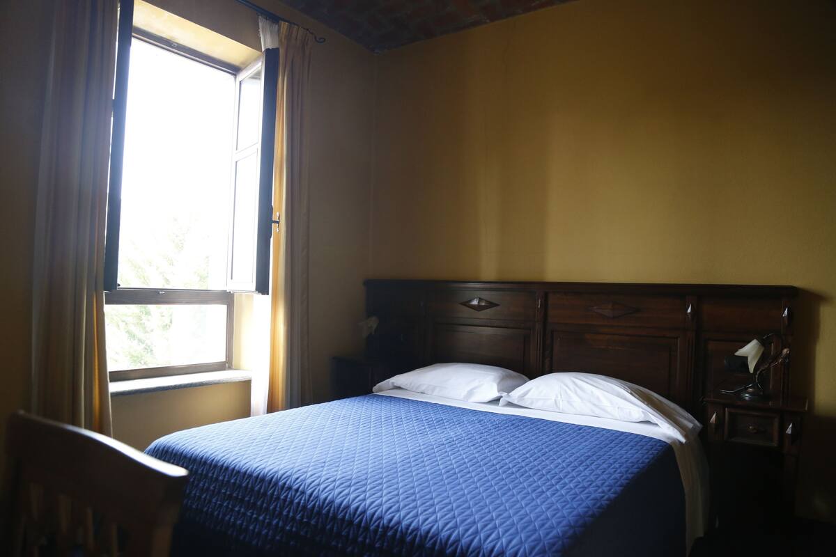 Un dormitorio con una cama, una ventana y una mesita de noche.