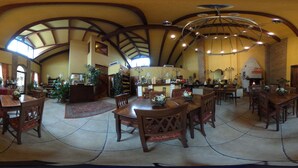A spacious dining area with high ceilings and wooden beams, featuring multiple dining tables and chairs. - Hotel Damian (Trofarello)