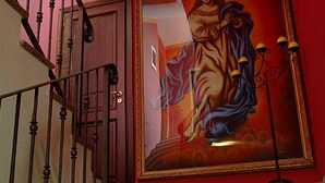 A staircase with a handrail, a framed painting on the wall, and a door at the bottom. - Hotel Damian (Trofarello)